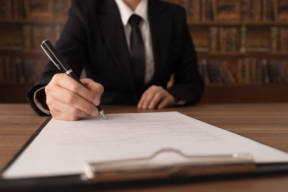 person in suit signing a formal document