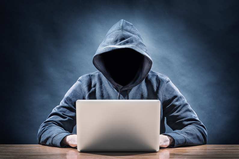 Faceless man in hoodie at a laptop