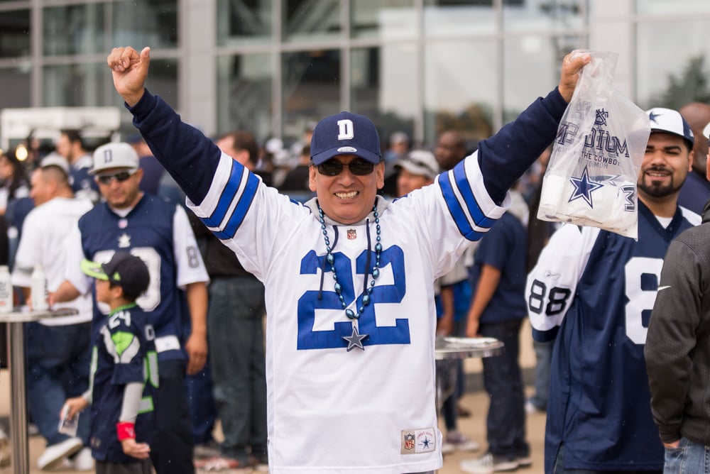 Dallas Cowboys fan in team gear with arms raised